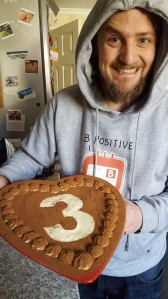 George showing off a heart-shaped cake with 3 on the top